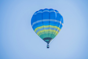 Naklejka premium Colorful balloon above a flower field at a national balloon festival,