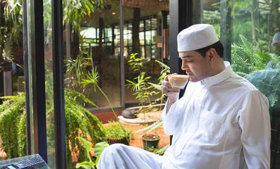 Asian mid aged muslim business man sit in coffee shop drink coffee
