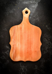 Cutting wooden board on a dark background. Top view. Free space for text. Background for food.