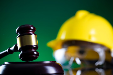 Labour law and builiding law concept.  Gavel and yellow crash helmet on the shining lawer desk.