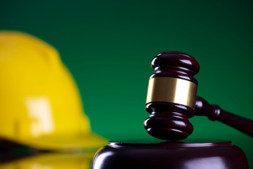 Labour law and builiding law concept.  Gavel and yellow crash helmet on the shining lawer desk.