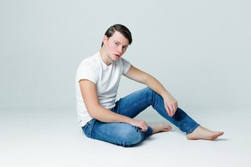 Handsome young man in a white T-shirt and with trendy hairdo on grey background