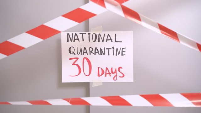 The elevator door with crossed protective red and white tape, insctiption on the paper National quarantine 30 days. Concept of antivirus programm of different countries, indoors