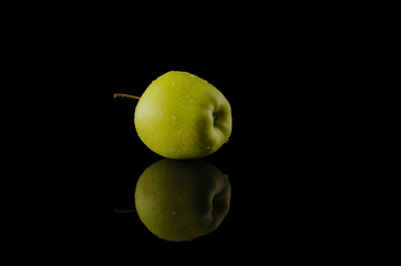 Fototapeta na wymiar green fresh Apple with water droplets on a glossy black background with reflection