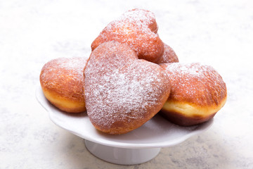 Homemade heart shaped donuts with powdered sugar on white background. Tasty doughnuts, copy space