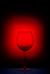 Naklejka na ściany i meble empty wine glass on the table on a red dark background