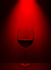 a glass of red wine in a red light on a glass table