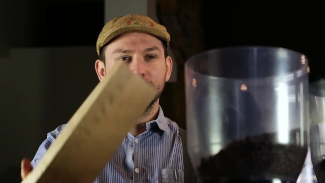 Close-up of a vintage barista man doing coffee beans in a coffee grinder.