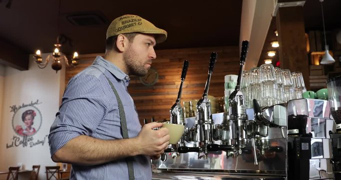 Medium shot of a vintage barista man tasting and drinking coffee. Tasting a cappuccino or espresso in a coffee shop