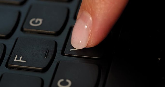 Black keyboard and a girl presses V button. English letters. Slow-mo and girl has a pink nail polish.