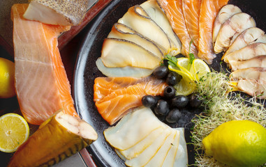 Fish set of varieties of fish,olives,red fish,salmon and seafood.The set is decorated with lemons and all products are laid out on a plate.