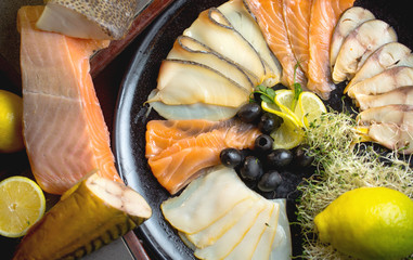Fish set of varieties of fish,olives,red fish,salmon and seafood.The set is decorated with lemons and all products are laid out on a plate.
