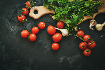 Fresh healthy vegetables for a salad. Cherry tomatoes and parsley, dill. Cutting board. Dark background. Free space for text.