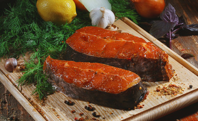 Pickled raw red fish lies on a light board with dill, lemon and seasonings.