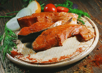 Pickled raw red fish lies on a light board with dill, lemon and seasonings.