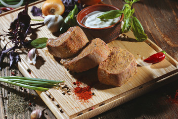 Pickled raw meat lies on a light board with white sauce, red pepper, basil, garlic and seasoning.