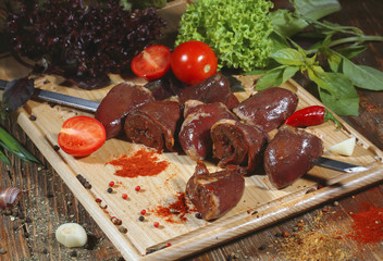 Pickled raw meat lies on a light board with tomatoes cherry, red pepper, basil and seasoning.