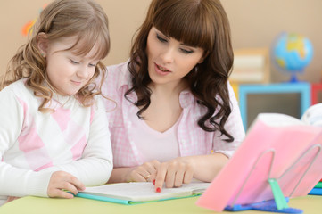 Fototapeta premium Close up portrait of mother with daughter doing homework