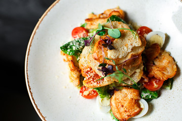 Caesar salad in a unique serving in a white plate on a dark background. side view. close-up