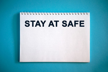 STAY AT SAFE text on a notepad on a blue background