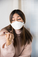 A teenager with a protective mask thinking that it is impossible to apply a lipstick with the mask

