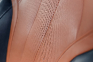 Part of stitched leather brown leather car interior. Modern luxury car black and brown perforated leather interior. Car leather interior details. Decorative seam