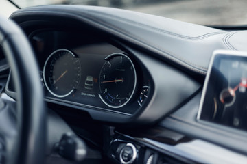 Glowing beautiful dashboard of a modern expensive car. The interior of the car. The foreground is blurred. Modern car interior details. Car detailing. Selective focus
