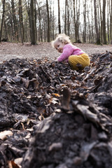 petite fille joue dans les bois, feuilles et ornières