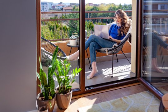 Beautiful young woman working from home on the balcony