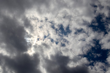 Cloudy sky with patches of blue and the sun hidden behind the clouds. Image taken in quarantine confinement by COVID-19