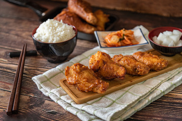 Closed up home made fried chicken with Korean source with garlic, spicy and steamed rice on wooden background, Korean food