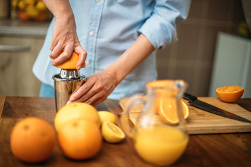 Young woman making juice from fresh oranges at home