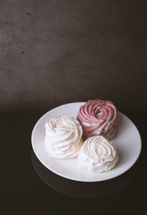 White and pink marshmallows shot on a dark background
