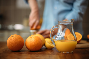 Young woman making juice from fresh oranges at home