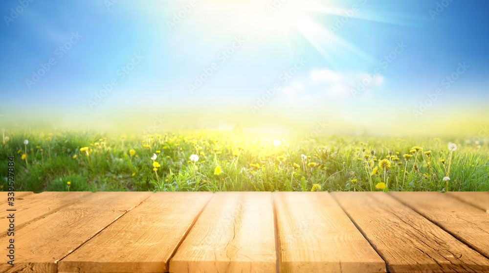 Poster spring summer beautiful background with green juicy young grass and empty wooden table in nature out