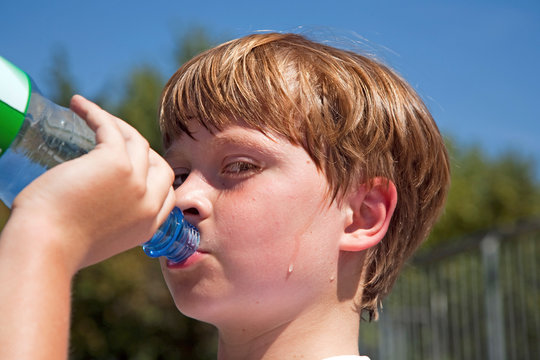 boy is sweating and thursty  and drinks mineral water