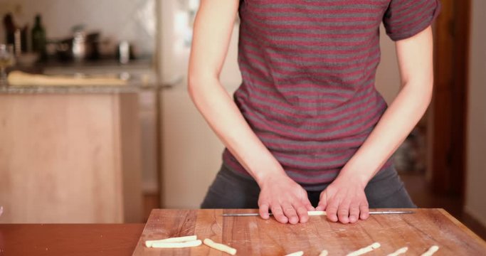 close up of young girl coocking traditional italian pasta fresca with hands flour baking pastry at home,  lady housewife cooking in cozy kitchen alone preparing food on a wooden table