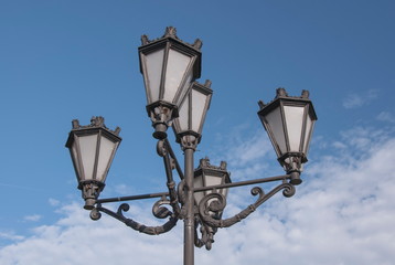 Fototapeta na wymiar Elegant metal street lights amid blue skies and white clouds