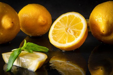 half  yellow  lemons on a  black with reflection , whole  citrus,  Basil, close up