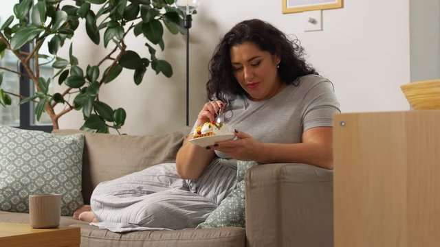 food, diet and people concept - happy smiling young woman eating cake at home