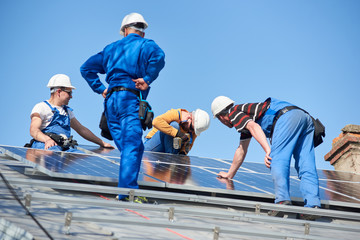 Male team engineers installing solar photovoltaic panel system. Electricians mounting blue solar...