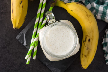 Banana smoothie in jar on black slate background