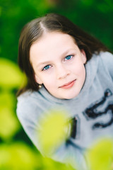 Young smiling pretty hipster girl is wearing warm gray blouse in park, summer time