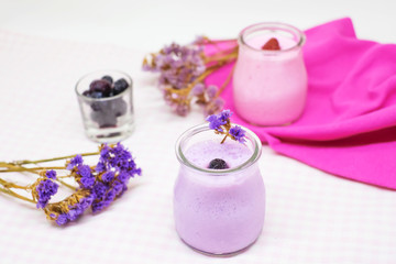 Obraz na płótnie Canvas Blueberry and strawberry jelly mousse in glass cups with pink and purple dry flowers