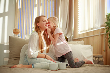 Young mother with daughter child play fun at home in bed, happy leisure lifestyle