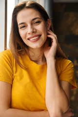 Fototapeta premium Image of pleased woman looking at camera and smiling while standing