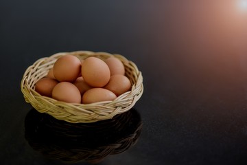Many Fresh eggs in a wicker basket on a black stone table in the kitchen, Ingredients prepared for cooking 