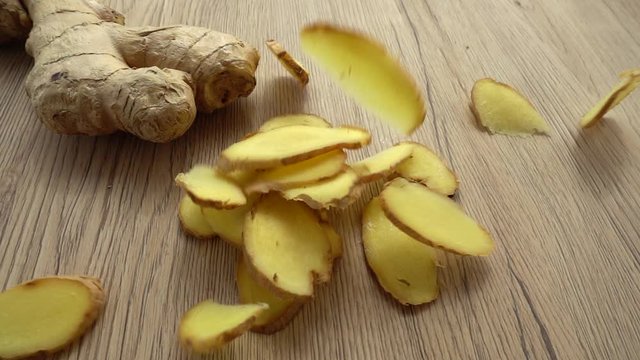 The sliced ginger root falls on a wooden surface. Slow motion.
