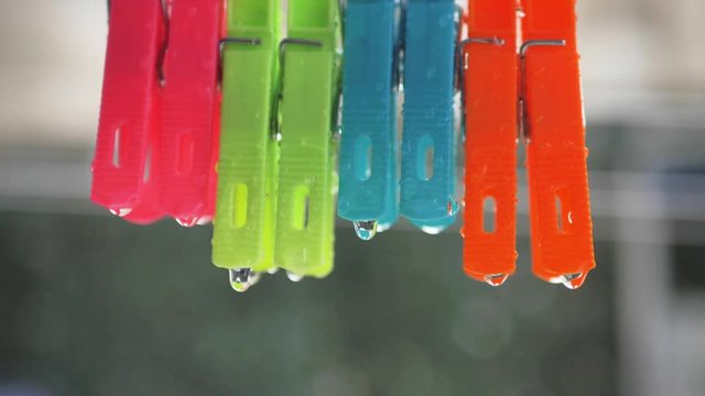 Pinzas de colgar ropa de colores bajo lluvia en c&aacute;mara lenta