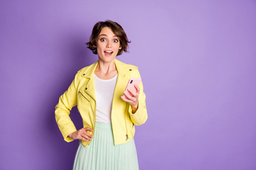 Portrait of astonished funky girl use smartphone impressed by followers subscribers in her social media account scream wow omg wear yellow clothes isolated over violet color background